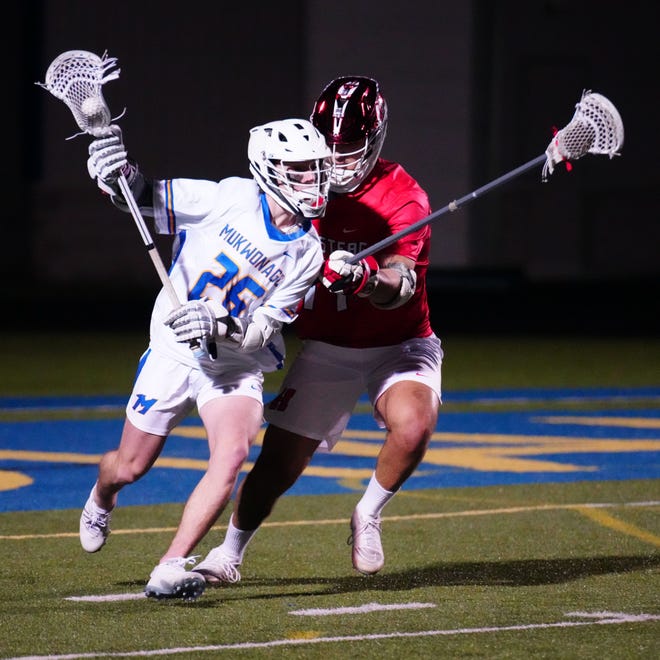 Mukwonago's Robert Spielmann (26) works to get past Homestead's David Foster (14) during the boys lacrosse match at Mukwonago on Tuesday, March 19, 2024.